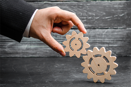 hand of a businessman adds a gear to a large gear