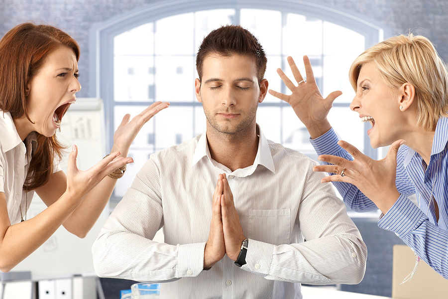 Two women yelling at a man in a calm position.