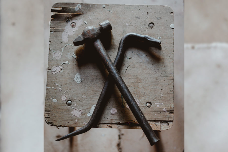 A hammer and crowbar sit on top if a cinder block