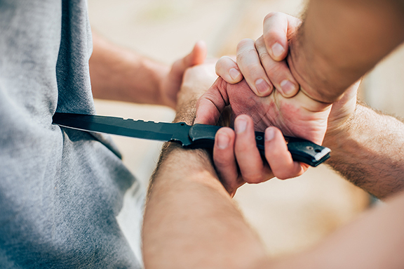 Kapap instructor demonstrates martial arts self defense knife attack disarming technique against threat and knife attack. Weapon retention and disarm training. Demonstration with a real metal knife