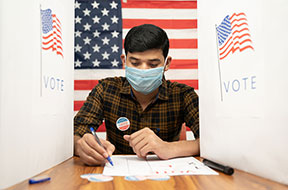 Young man in a medical mask busy inside the polling booth