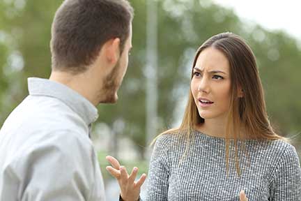 Couple talking seriously outdoors in a park with a green background