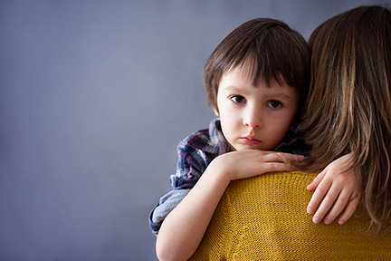 Sad little child boy hugging his mother at home